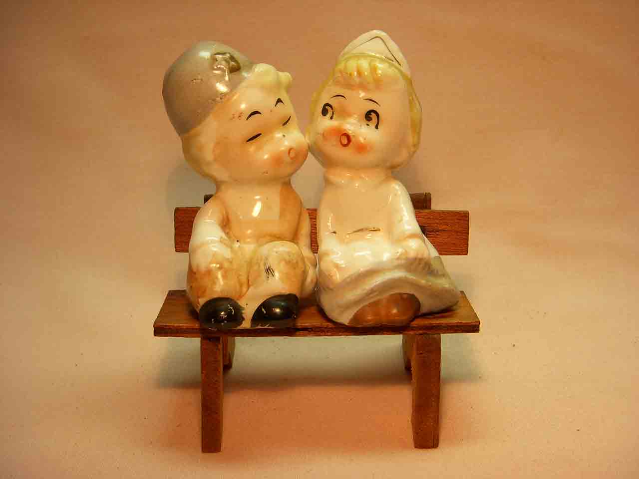 Little boy and nurse girl sitting on wooden bench salt and pepper shaker